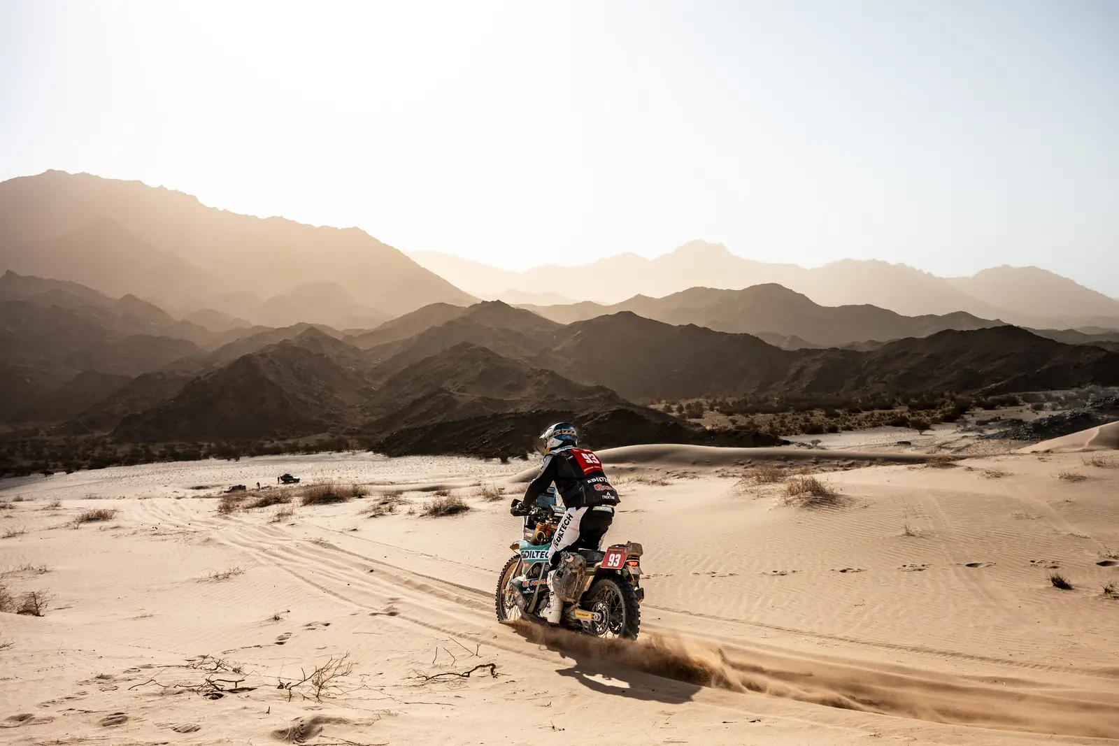 Un pilota attraversa una valle sabbiosa ai piedi delle montagne, Dakar 2026